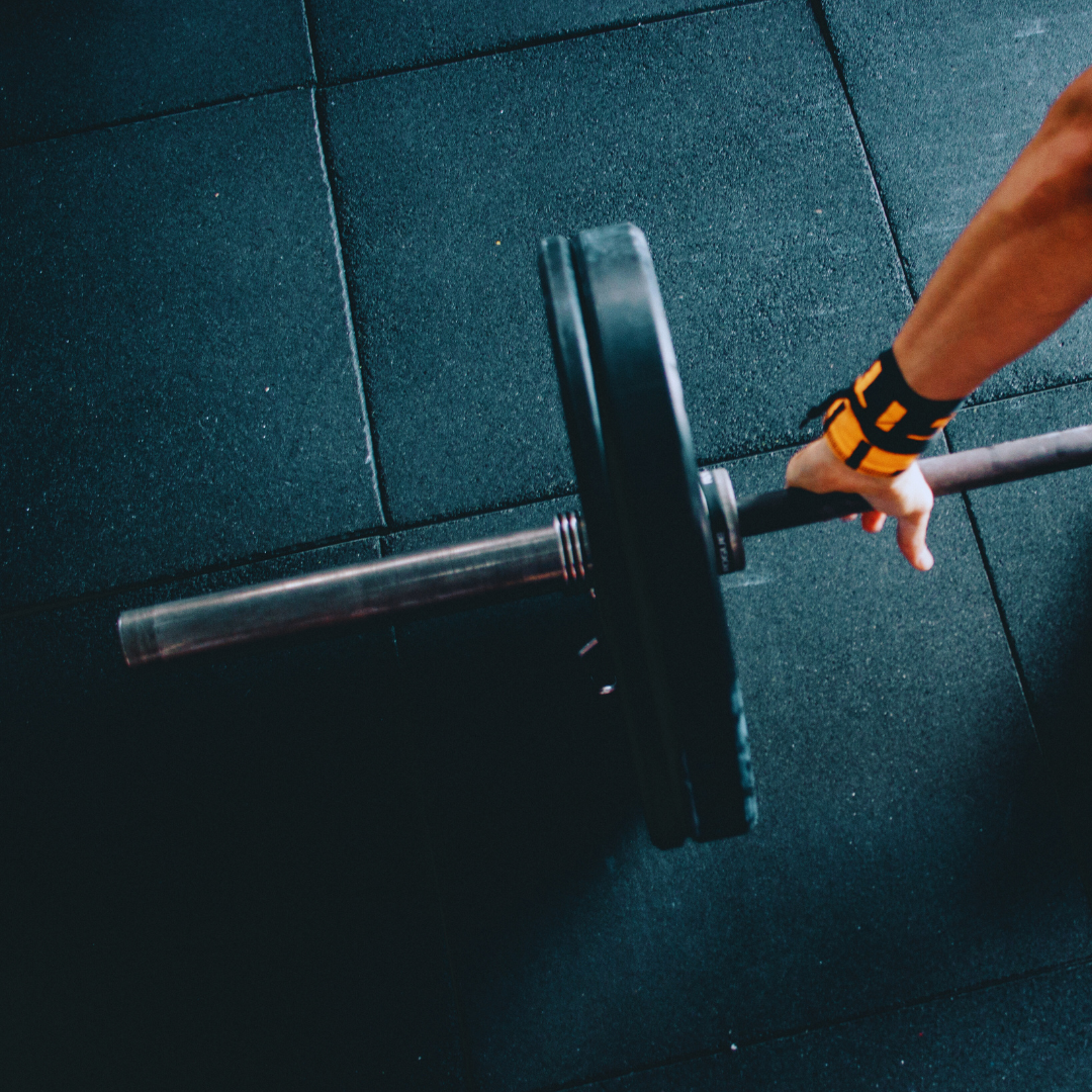 person with their hand on a barbell and a weight