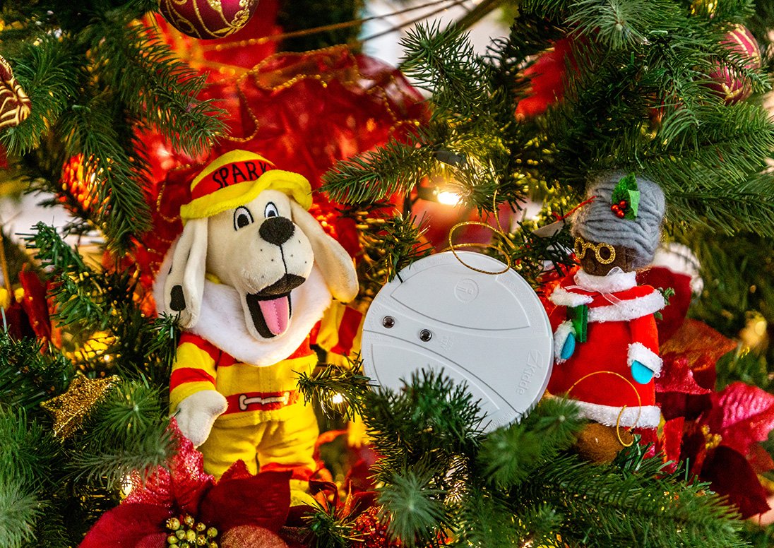 Sparky the Fire Dog with a smoke detector in a Christmas tree