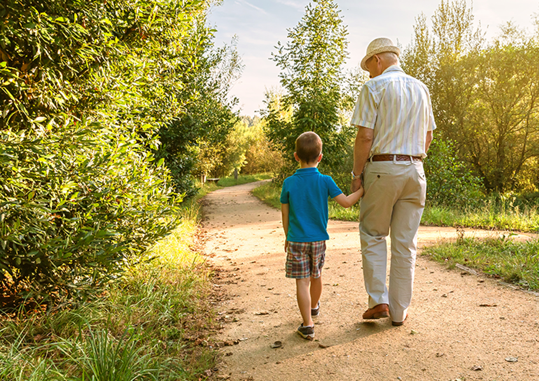 A grandfather and a child walking on a trail