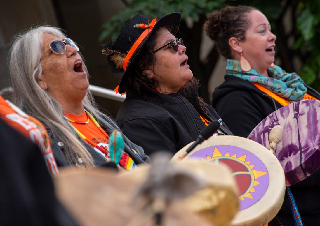 Three Indigenous women singing and drumming at a past year's City commemoration of Orange Shirt Day.