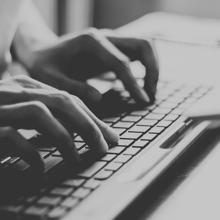 hands typing on a computer in black and white